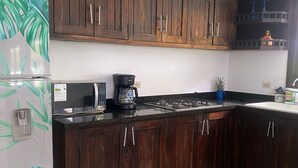 A kitchen with dark wooden cabinets, a white refrigerator, a coffee maker, and a potted plant. - Marina Private Villa (Zarzal)