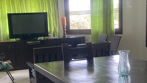 A dining area with a long table, benches, and a television on a cabinet. - Marina Private Villa (Zarzal)