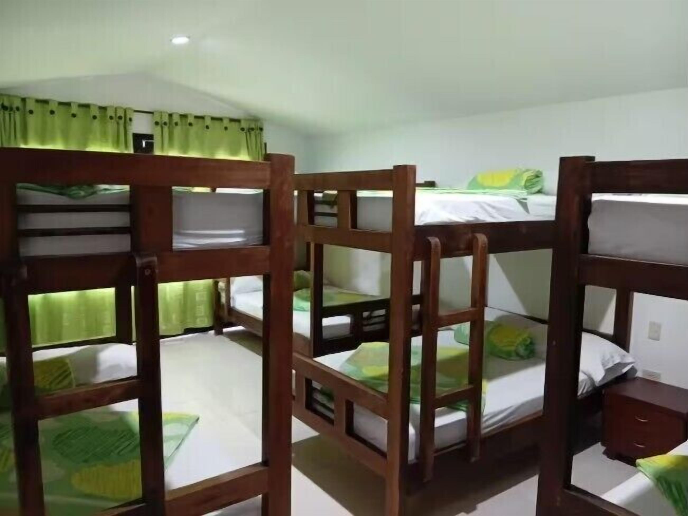 Una habitación con literas, una mesita de noche pequeña y una ventana con cortinas.