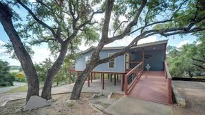 Une maison dotée d’une terrasse en bois et d’un escalier menant à un porche.