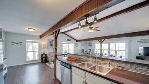 Une cuisine spacieuse dotée d’un grand îlot central, de poutres en bois et d’un robinet moderne.