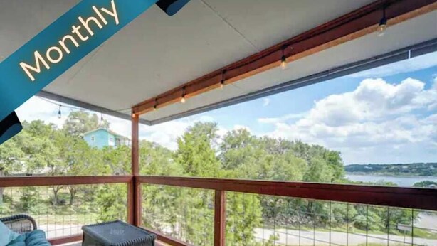 Un balcon extérieur abrité, offrant une vue sur des arbres et une étendue d’eau.