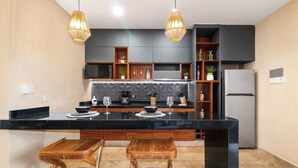 A modern kitchen with a black countertop, wooden stools, and pendant lights. - One-bedroom retreat with a private pool patio: your oasis in Tulum! (Tulum)