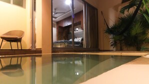 A room with a glass door leading to a bedroom, a chair, and a potted plant. - One-bedroom retreat with a private pool patio: your oasis in Tulum! (Tulum)