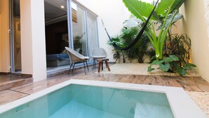 A swimming pool with a wooden deck, a chair, and a large plant. - One-bedroom retreat with a private pool patio: your oasis in Tulum! (Tulum)