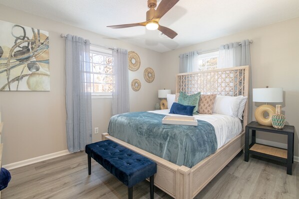 A bedroom with a bed, a bench, a ceiling fan, and a bedside table with a lamp. - Graham Getaway Near Elon University (Graham)