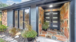 A modern house with a stone exterior, a black door with glass panels, and a 'hello' mat at the entrance. - Beautiful Lake getaway with pool, upgraded, pet friendly with lots of extras!! (Green Cove Springs)