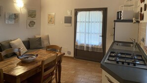 Une cuisine chaleureuse avec une table en bois, un poêle et un coin repas comprenant un canapé et des chaises.