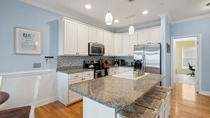 A modern kitchen with white cabinets, granite countertops, stainless steel appliances, and a bar seating area. - 20 Turtle Bay! 30 Night Minimum Stay - River View, Community Pool & Dock (Folly Beach)