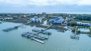 An aerial view of a coastal property with multiple docks extending into the water, surrounded by residential buildings and a clear view of the ocean. - 20 Turtle Bay! 30 Night Minimum Stay - River View, Community Pool & Dock (Folly Beach)