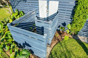 Garden area features a compost bin surrounded by lush greenery and a neatly trimmed lawn.