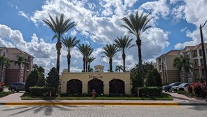 A resort entrance with palm trees, a sign reading "Vista Cay Resort", and a paved pathway. - Vista Cay 102 | Steps from Universal's Epic Universe & Convention Center | No Stairs, Fast Wi-Fi! (Orlando)