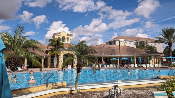 A pool area with multiple pools, palm trees, and a building with a tiled roof. - Vista Cay 102 | Steps from Universal's Epic Universe & Convention Center | No Stairs, Fast Wi-Fi! (Orlando)