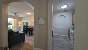 A modern living room with a dark sofa, a dining area with a table and chairs, and a kitchen with cabinets and a countertop. - Vista Cay 102 | Steps from Universal's Epic Universe & Convention Center | No Stairs, Fast Wi-Fi! (Orlando)
