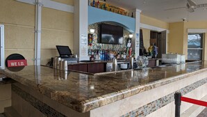 A bar area with a marble countertop, a cash register, and a variety of liquor bottles. - Vista Cay 102 | Steps from Universal's Epic Universe & Convention Center | No Stairs, Fast Wi-Fi! (Orlando)