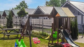 A playground with a swing set, slide, and picnic tables. - 1 bedroom amazing home in Ustronie Morskie (Ustronie Morskie)