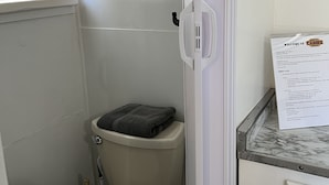 A compact bathroom with a toilet, a towel rack with folded towels, and a welcome sign. - Quaint Cabin #1 - Pymatuning Lake (Jamestown)
