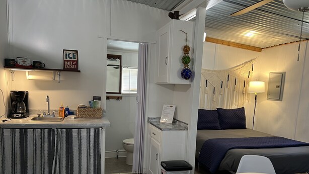A compact hotel room with a kitchenette, a bed, a small table, and a bathroom. - Quaint Cabin #1 - Pymatuning Lake (Jamestown)