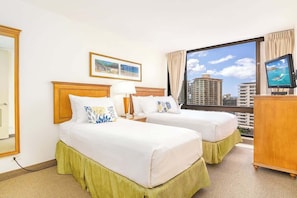 Quarto de hotel com duas camas, televisão, janela com vista para a cidade e um quadro pendurado na parede.
