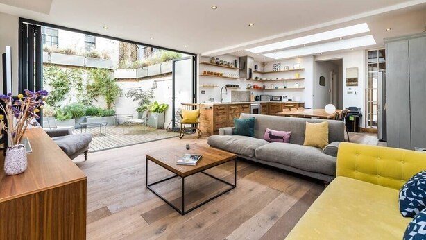 A modern living room with a sofa, coffee table, and a dining area with a kitchen in the background. - Stunning 3BD Flat Shoreditch with Hidden Garden (London)
