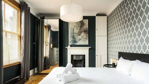 A hotel room with a large bed, a fireplace, and a view of the hallway. - Beautiful 3BD Home Forest Hill South London (Greater London)