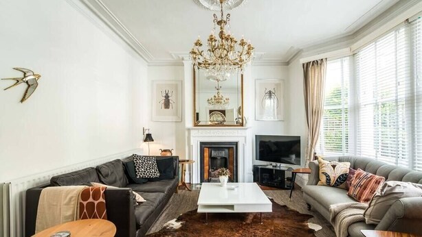 A living room with a fireplace, a chandelier, and a television. - Beautiful 3BD Home Forest Hill South London (Greater London)