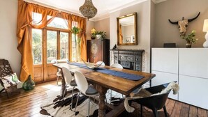 A dining room with a wooden table, white chairs, a chandelier, and a fireplace. - Beautiful 3BD Home Forest Hill South London (Greater London)