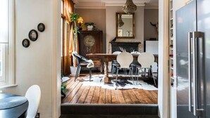 A dining area with a wooden floor, a fireplace, and a modern chandelier. - Beautiful 3BD Home Forest Hill South London (Greater London)