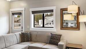 Un salón moderno con un sofá modular, una mesita auxiliar y un espejo grande con luces colgantes.