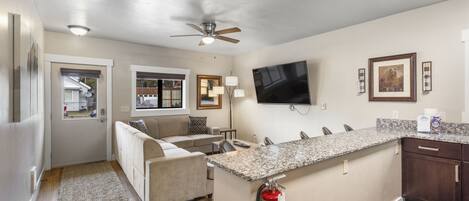 A modern kitchen with a granite countertop, a built-in oven, and a ceiling fan.