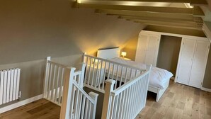 Un dormitori amb un llit, un armari blanc i una escala.