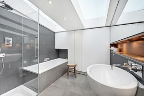 Un baño moderno con cabina de ducha de vidrio, una bañera grande y un tocador con espejo.