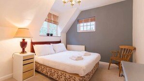 Een slaapkamer met een bed, bedlamp, houten stoel en een kroonluchter.