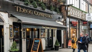 Une vue de rue avec un restaurant appelé « Three Compasses » et un magasin appelé « Coco ».
