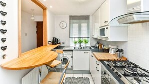 A compact kitchen with a wooden dining table, a built-in washing machine, and a gas stove.