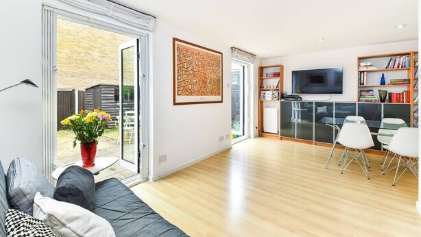 A modern living room with a sofa, a coffee table with flowers, a TV, and a bookshelf.