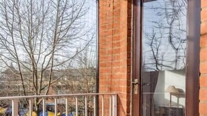 A balcony with a metal railing, a glass door, and a view of tents outside. - NEW Bright and Sunny flat in Oxford City Centre (Oxford)