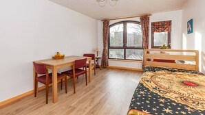 A bedroom with a wooden bed, a desk with chairs, a window with curtains, and a chandelier. - NEW Bright and Sunny flat in Oxford City Centre (Oxford)