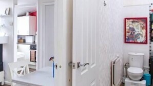 Een witte kamer met een eettafel en stoelen, een wit toilet en een radiator.