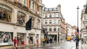 A street with shops, including a Versace store, and a pedestrian crossing. - A Stunning Three Bedroom Home in Mayfair (Greater London)