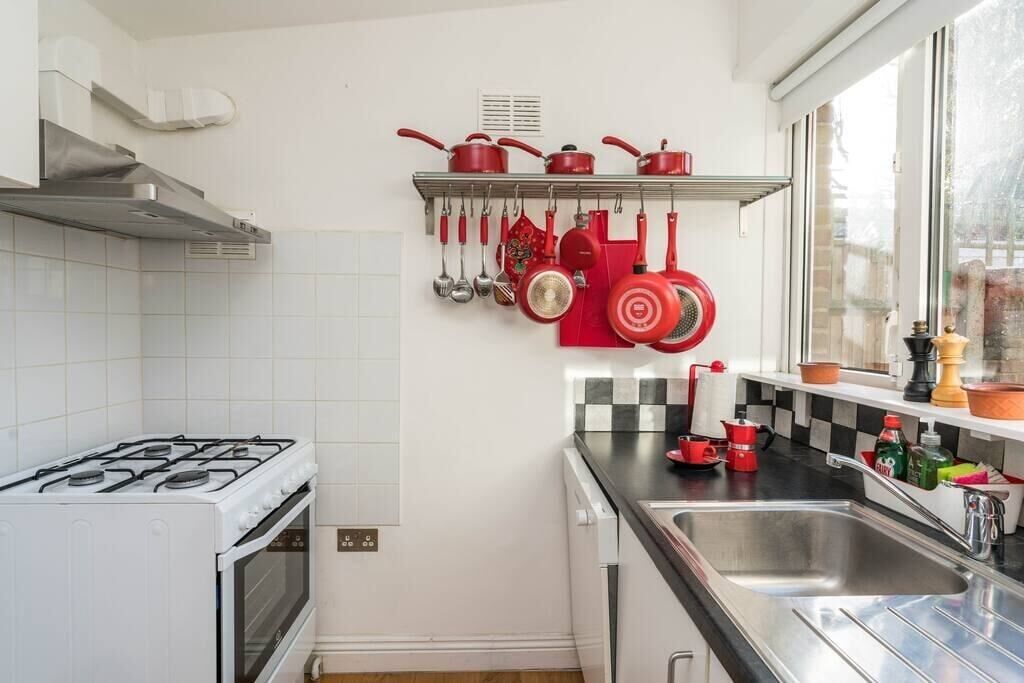 Una cocina con armarios blancos, una estufa a gas, un fregadero y una ventana con vistas al exterior.