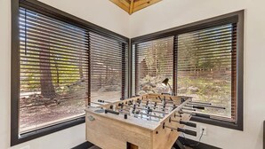 Un tavolo da calcio inglese in una stanza angolare con ampie finestre e soffitto in legno.