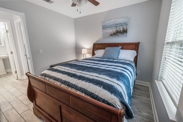 Un dormitorio con una cama de madera, una mesita de noche, una lámpara y un cuadro en la pared.