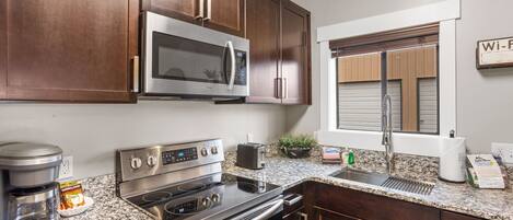 Una cocina moderna con electrodomésticos de acero inoxidable, gabinetes de madera oscura y encimera de granito.