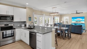 Una cocina moderna con encimeras de granito, electrodomésticos de acero inoxidable y una isla central con taburetes de bar.