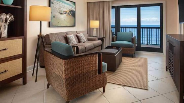 Un salón con sofá, sillones, una mesa de centro, televisor, estantería y un cuadro.