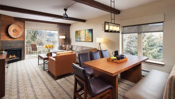 A spacious living area with a fireplace, a dining table, and a sofa. - Sheraton Lakeside Terrace Villas at Mountain Vista - 2 Bedroom Villa (Avon)