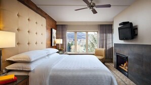 A hotel room with a large bed, a television mounted on the wall, a fireplace, and a view of the mountains through the window. - Sheraton Lakeside Terrace Villas at Mountain Vista - 2 Bedroom Villa (Avon)