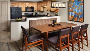 A modern kitchen with wooden cabinets, a black refrigerator, and a dining area with a wooden table and chairs. - Sheraton Lakeside Terrace Villas at Mountain Vista - 2 Bedroom Villa (Avon)