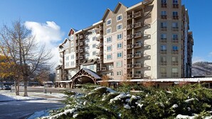 A multi-story hotel with balconies, a covered entrance, and snow-covered landscaping.
